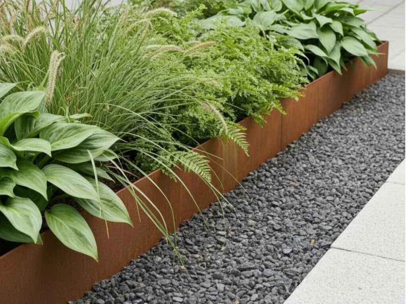 Bedkant i cortenstål med planter langs grussti i hage