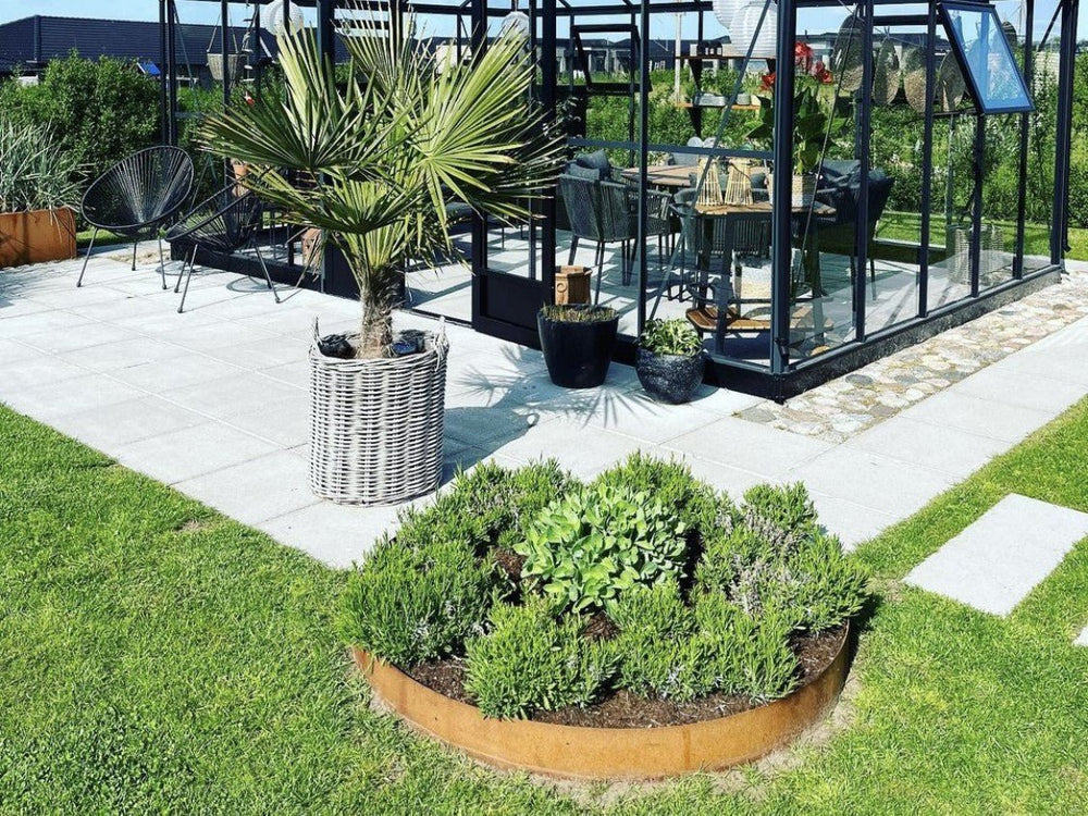 Lav rund bedring i cortenstål med planter ved terrasse