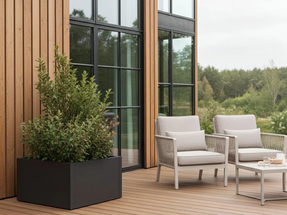 byJEMA CUBY plantekasse i svartlakkert stål på terrasse ved loungemøbler