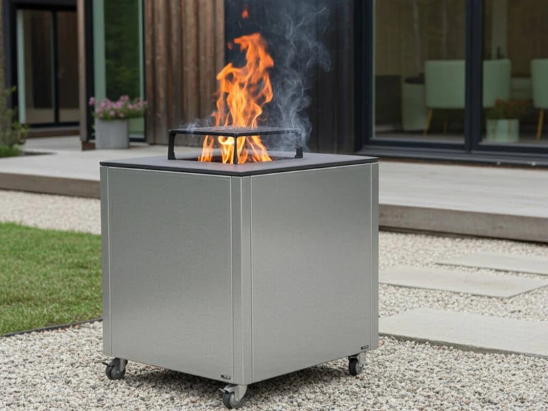 CUBY bålgrill i galvanisert stål på terrasse ved hus med planter og synlige flammer