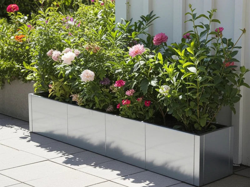 Lang plantekasse i galvanisert stål fra CUBY med blomstrende planter