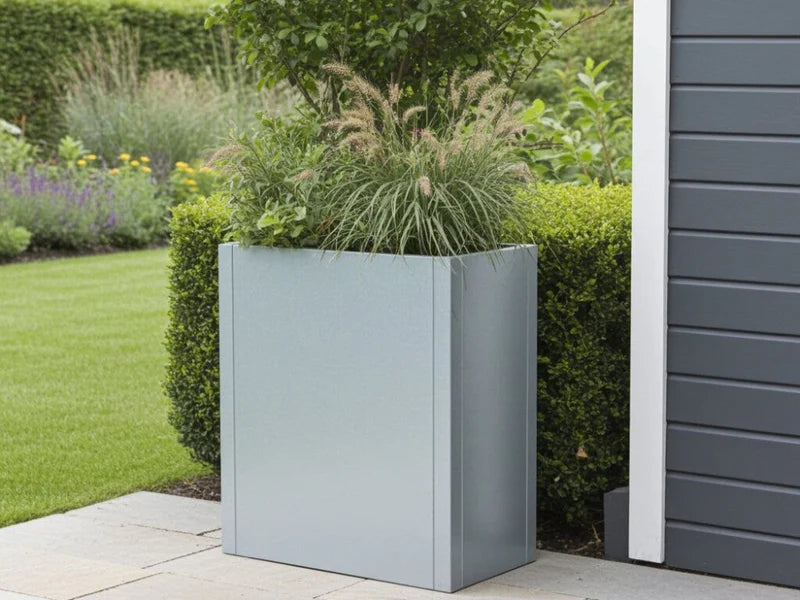 CUBY høy plantekasse i galvanisert stål med prydgress ved moderne fasade