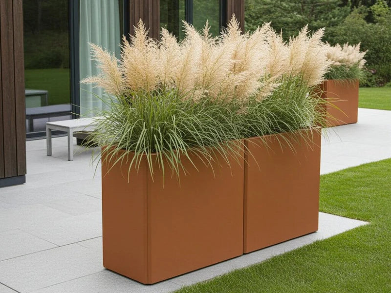 EDGY høy rektangulær plantekasse i cortenstål med prydgress ved terrasse