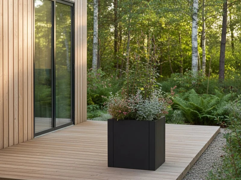 Kvadratisk plantekasse i svart stål med planter på treterrasse