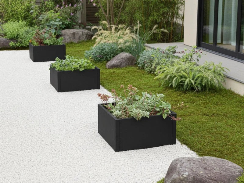 Plantekasser i svart stål med stauder i moderne hage med steinbed