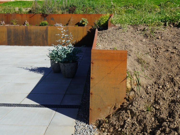 Endeplate til støttemur i cortenstål i plantebed