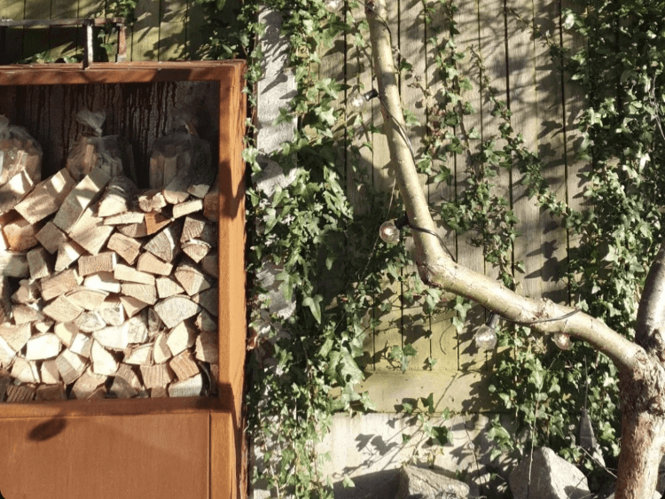 Detaljbilde av vedoppbevaring i cortenstål med stablet ved