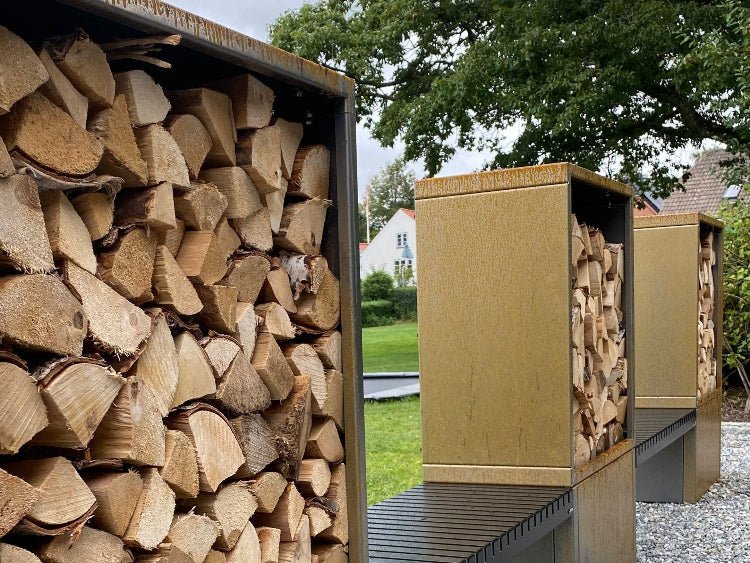 Detaljbilde av stablet ved i vedstativ av cortenstål med sittebenk