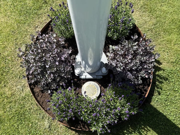 Rund bedring i cortenstål rundt flaggstang med blomster