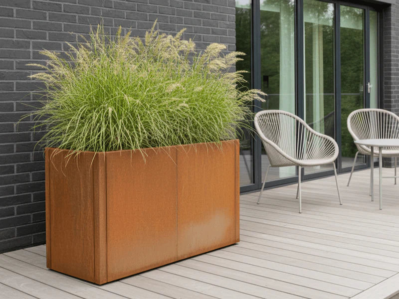 Plantekasse i cortenstål fra CUBY med fyldig beplantning på treterrasse