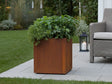 CUBY plantekasse i cortenstål med frodige planter i hage