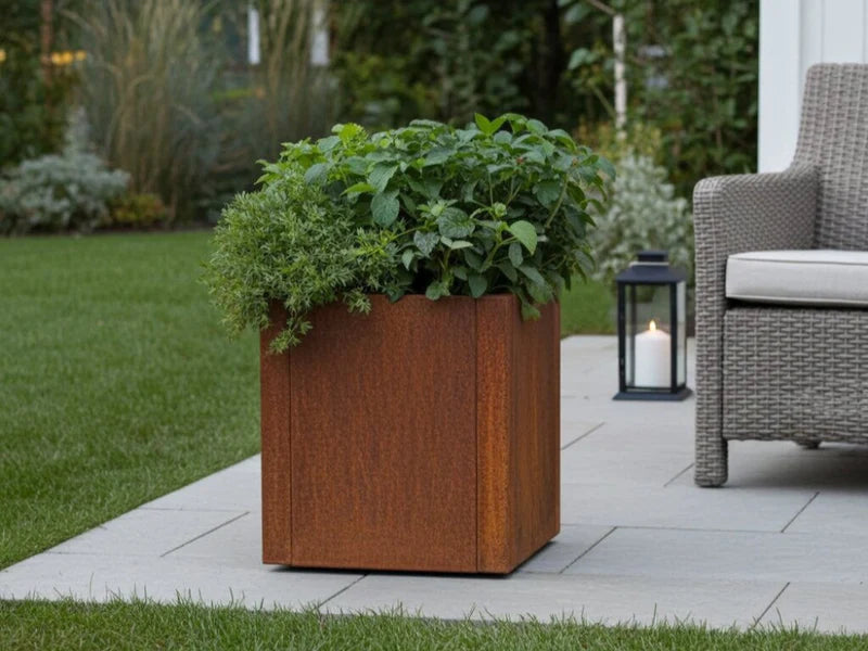 CUBY plantekasse i cortenstål med frodige planter i hage
