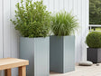 CUBY plantekasse i galvanisert stål plassert på moderne terrasse med grønne planter