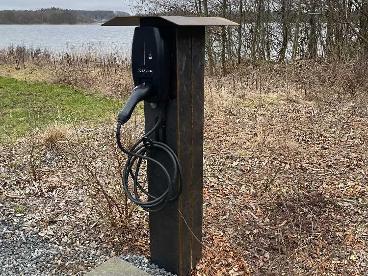 Frittstående ladestolpe i cortenstål plassert i naturlige omgivelser