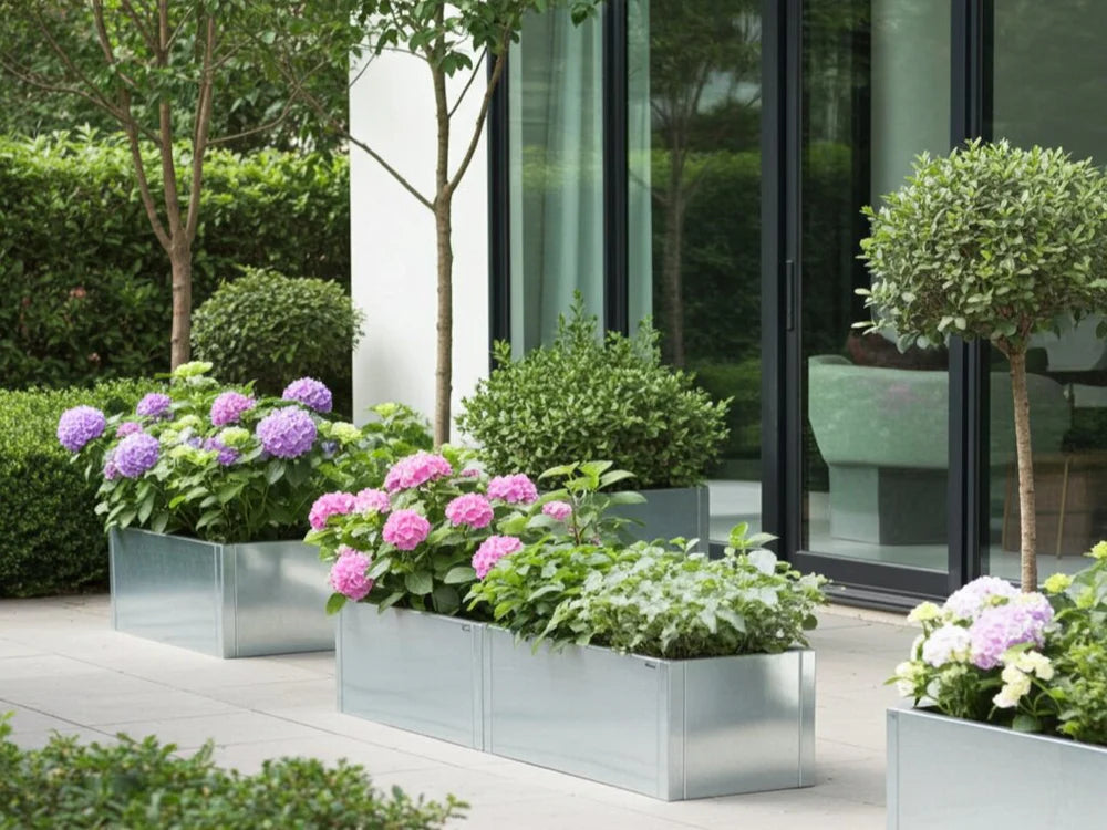 Lang plantekasse i galvanisert stål med blomster og busker ved terrasse