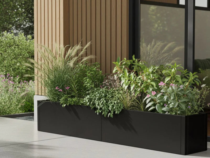 Plantekasse i svart stål med prydgress ved terrasse