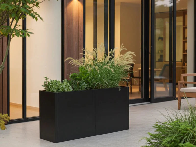 Plantekasse i svart stål med prydgress ved moderne terrasse