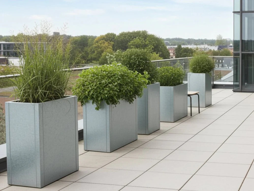 Store plantekasser i galvanisert stål med grønne planter på balkong