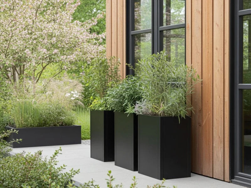 Høye plantekasser i svart stål ved moderne trefasade