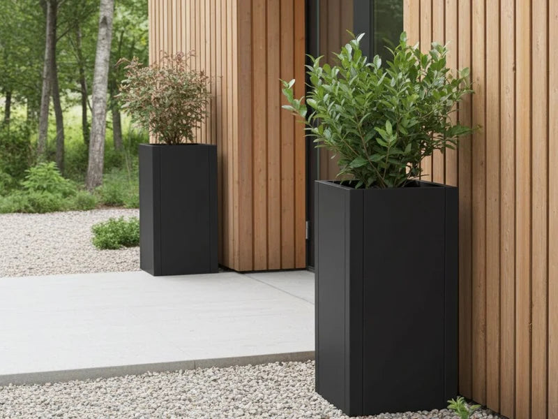Høye plantekrukker i svart stål ved inngangsparti